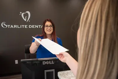 patient handing in her new patient information at Starlite Dental