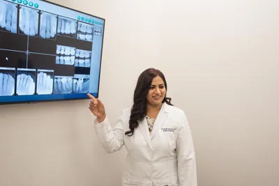 Dr. Jaiswal showing a patient their dental x-rays on the big screen
