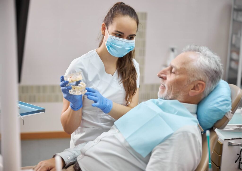 Dentist explaining dental implant treatment options to a senior patient during a restorative dentistry consultation