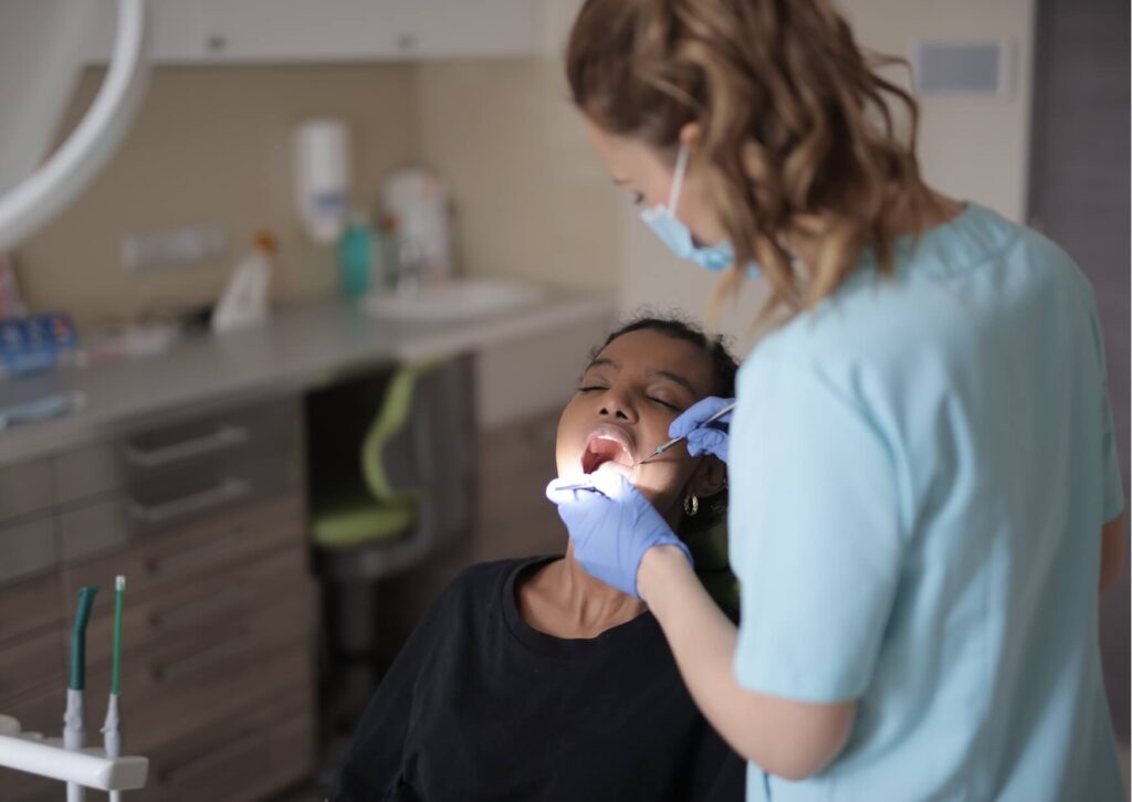 Dentist examining a patient's mouth to evaluate symptoms of a wisdom tooth coming in.
