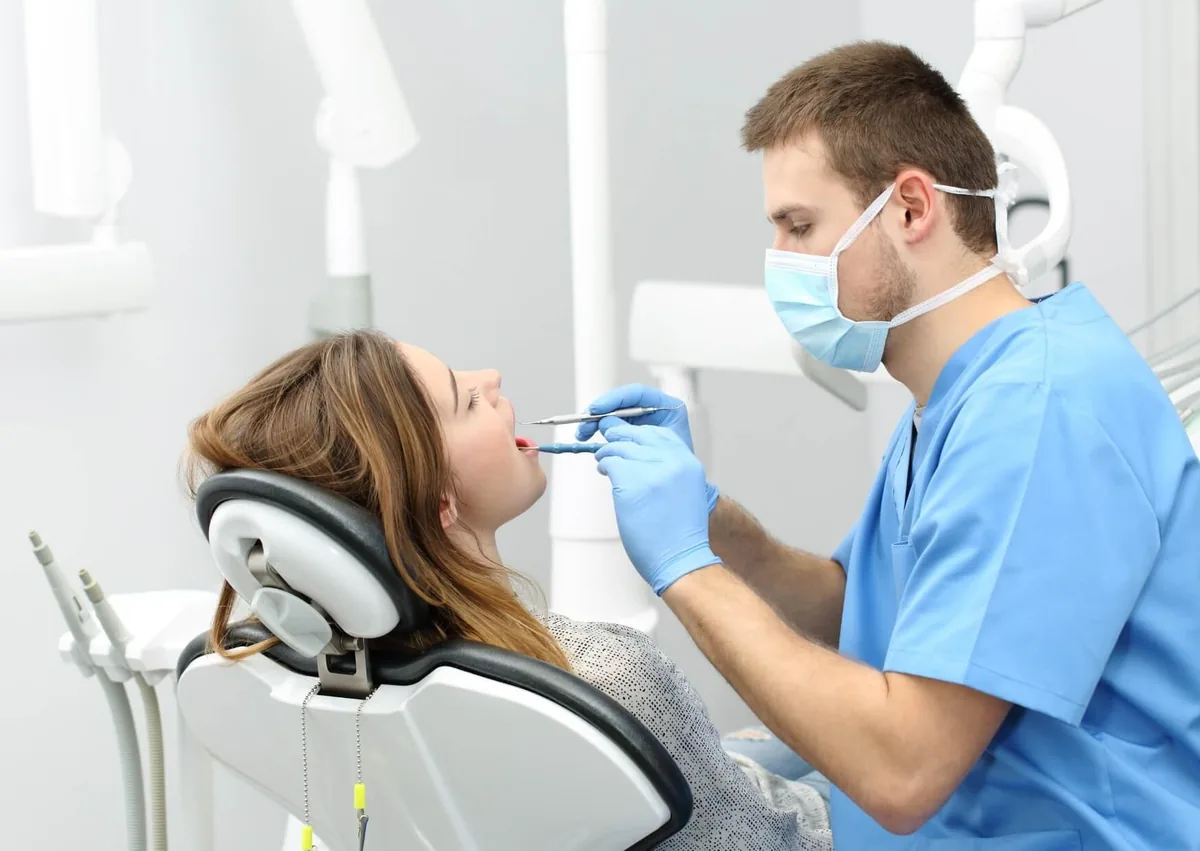 Dentist examining a patient to monitor healing of a normal tooth socket after extraction.