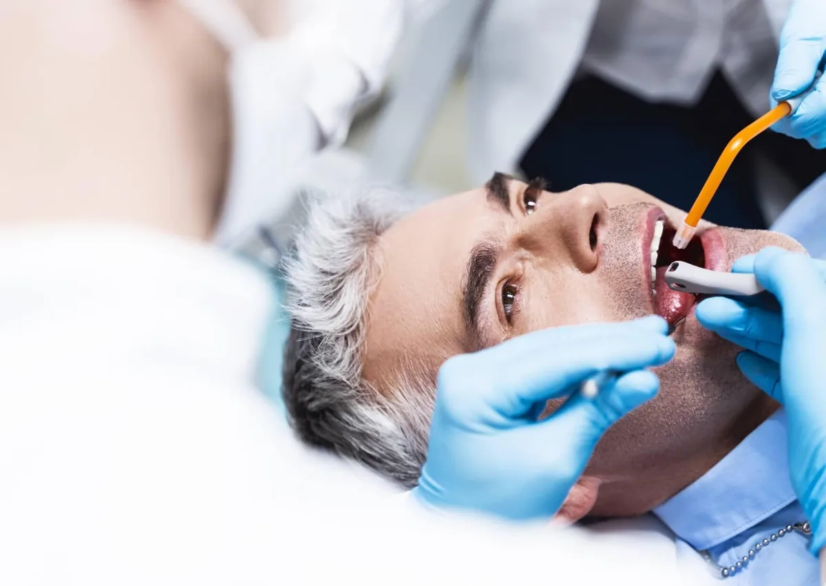 Dentist examining a patient to help maintain dental implants and support their long-term lifespan.